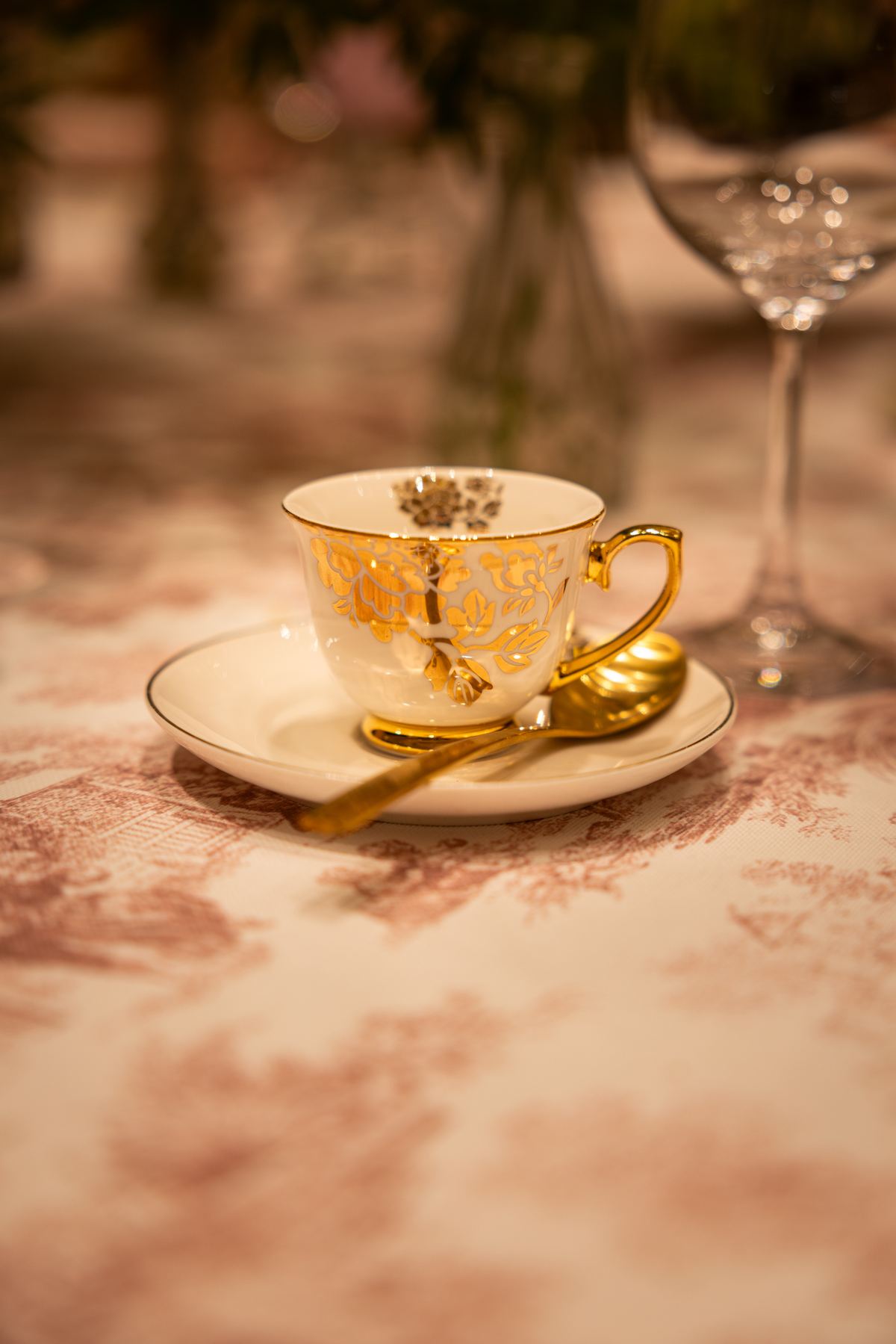 Gold teacup on a pink toile tablecloth