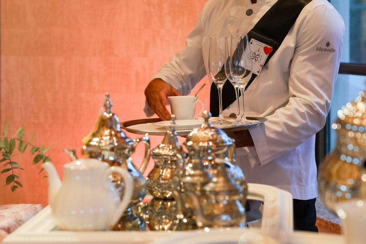 Waiter pouring tea from silver teapots