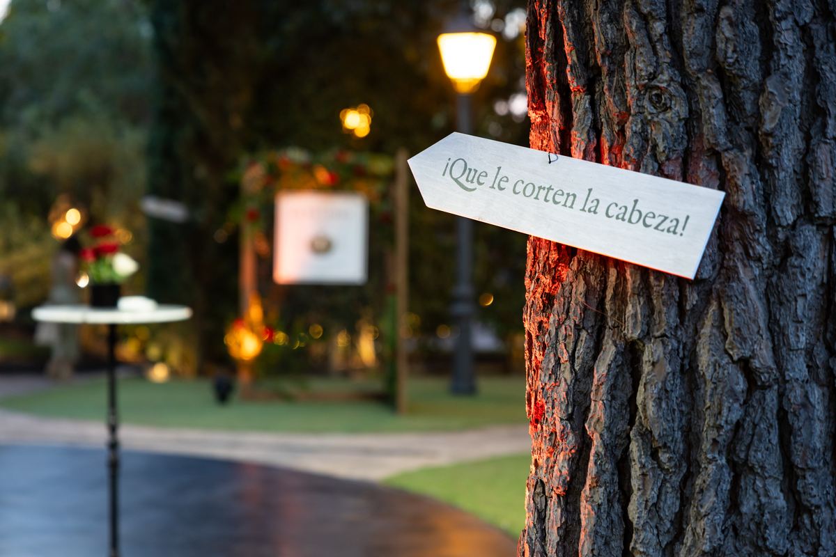 Sign reading “Off with her head!” nailed to a pine tree in the garden