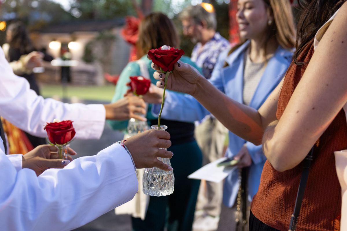 Red roses in a glass vase being handed to guests