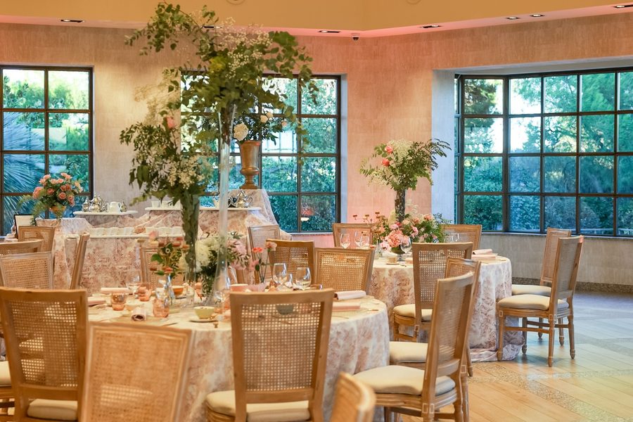 Salón de El Atrio con mesas redondas, plantas altas y ventanales al jardín