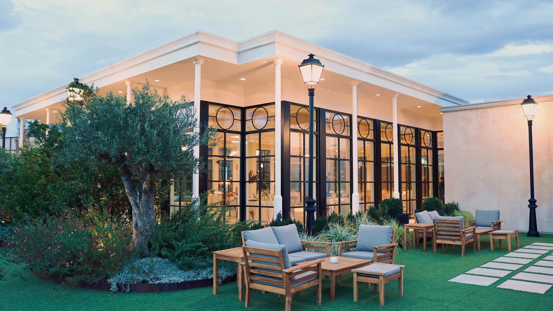 Exterior cristalero de La Galería con jardín y sillones