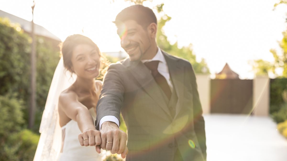A couple laughing in the garden as they show the ring