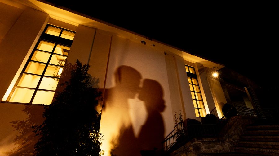Silueta de los novios besándose en la fachada iluminada de noche