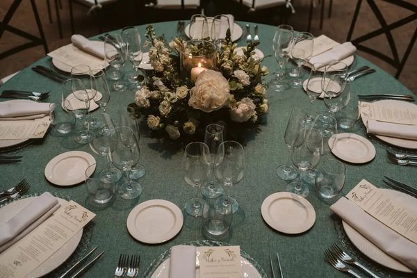Round table set with a white flower centrepiece and a candle at a celebration at Finca Miravalle